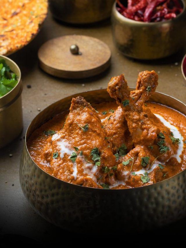 Creamy butter chicken with tender pieces in a rich tomato-based gravy, garnished with herbs.